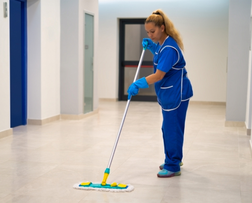 A Cleaning Lady Mops The Floor In An Office Building